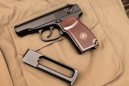 Pistol and clip. A pistol in the background of a jacket.の写真素材