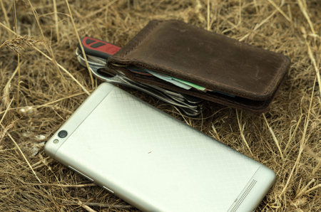 Mobile phone and knife in the manger. Multi-functional knife. Wallet with money.
