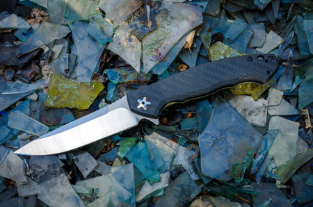 Zero tollerance knife on broken glass. Multicolored background.