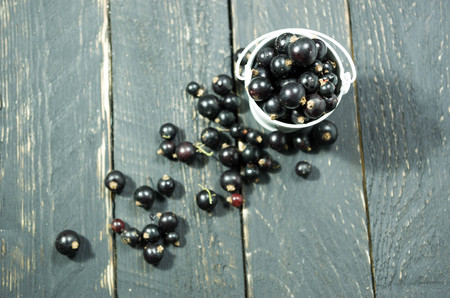 Black currant in white bucket. Dark wooden background.の写真素材