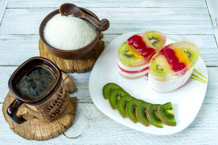 Serving coffee break. Cheesecake with fruit slices and sliced kiwi. Coffee on the table.