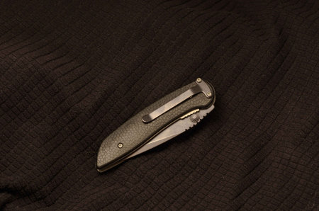 Black knife folded on a black background. Black textiles.