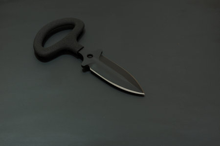 Black knife on a black background. A lot of air in the frame. Military composition.