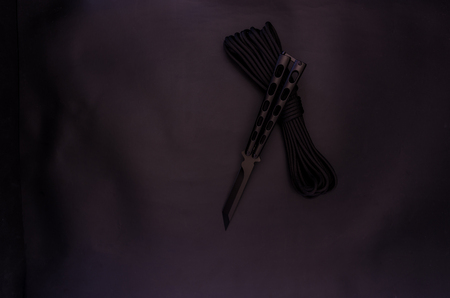 Black Butterfly Knife. Black rope on a black background. Top.の写真素材