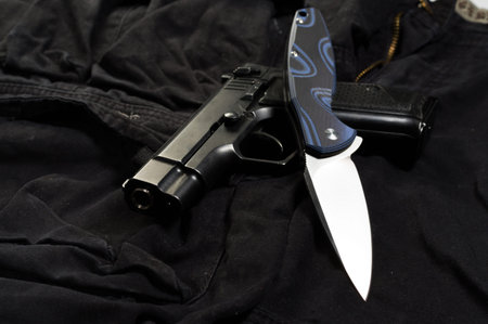 A set of weapons from a knife and pistol. White knife blade and black pistol. The foreground...