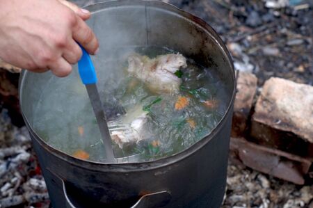 The cook stirs the broth. Cooking soup in nature. Cooking at the stake. Boil the broth.の写真素材