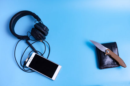 Big headphones and a mobile phone. Mens items on a turquoise background.