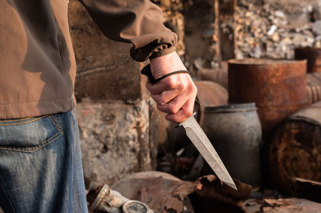 A man holds a large knife. The military holds a knife. Back view.