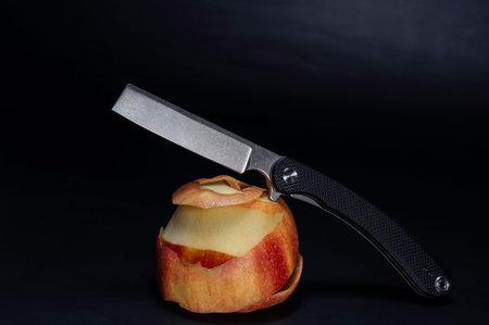 Knife and apple. A knife lying on an apple. A peeled apple.
