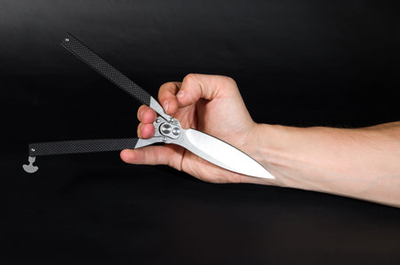 Folding knife with an unusual handle. The knife in the hand. Black background.