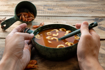 Red tomato soup with shrimp. Dish with tomatoes and prawns. Hands and food.の写真素材