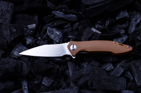 Pocket folding knife with a brown handle. Shiny knife on the corner. Color and contrast. Top.
