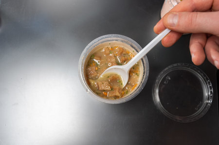 Cooked soup in a plastic glass. To eat soup from a glass.