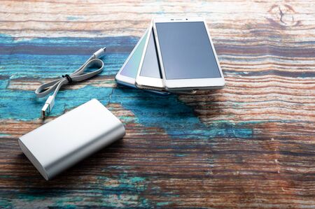 Charger and several smartphones. Mobile charger for smartphones. Mobile phones and power bank.の写真素材