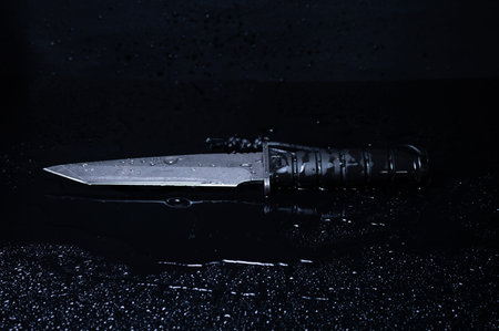 Large army knife with a fixed blade and a drop of water. Drops of water on the knife. Black on...