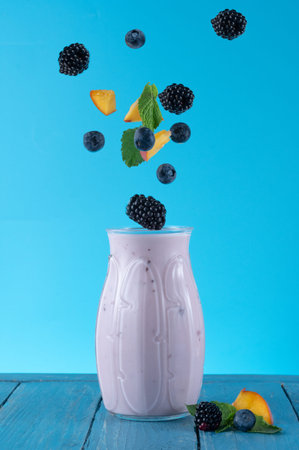 Berries over a glass. Blueberry and blackberry yogurt. Dairy products and berries. Floating berries...