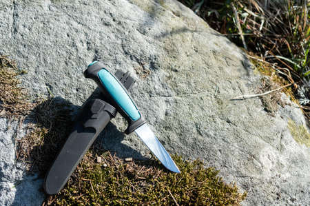Knife and scabbard on a stone with moss. Outdoor knife. Daylight.の写真素材