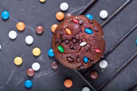 Chocolate muffin on a wire rack. Muffin sprinkled with multi-colored sweets.の写真素材
