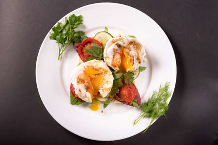 Poached eggs with herbs and vegetables. View from above. Black background.の写真素材