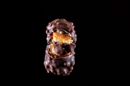 Chocolate candy with caramel and nuts. Broken candy into pieces. Stretching caramel. Chocolate candy isolate. Front view.の写真素材