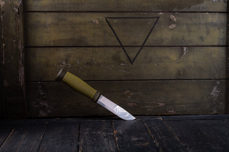 Scandinavian Swedish knife on the background of a green army box. Dark mood.