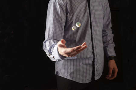 The man in the shirt throws the dice. Dice floating in the air.の写真素材