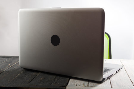 Laptop on the table. Computer on a wooden table. Dim lighting.