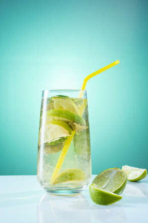 Cooking lemonade in a glass and a straw. Bright light composition. Lemonade with lime and mint.の写真素材