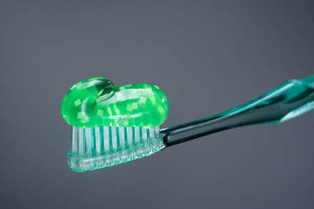 Green toothpaste. Toothpaste on a toothbrush. Toothpaste with additives. Gray background. Toothpaste isolate.の写真素材
