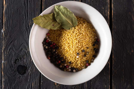 Millet and spices. Millet and bay leaves. Millet for cooking porridge. Millet in a plate. View from above.の写真素材
