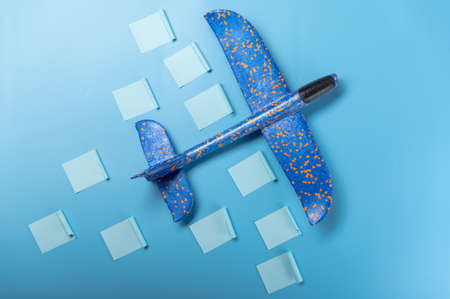 Airplane and stickers with tasks. Childrens plane on a blue background. Stickers with tasks on the table.の写真素材