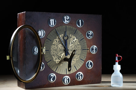 Old mechanical clock in a wooden case. Mechanical watch and oil. Clockwork mechanical watch. Desk...