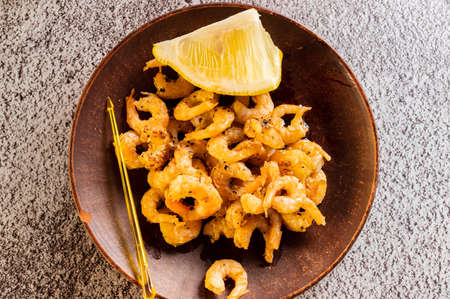 Clay plate with fried shrimp and lemon. Serving fried shrimp. View from above.の写真素材