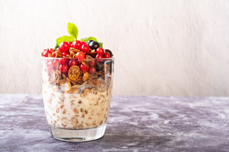 Fresh summer berries and granola in a glass. Snack of berries and granola with yogurt. One glass on...