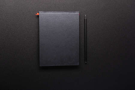Black notebook and black pen. Mystery magazine. Secret journal. Flat lay. View from above.の写真素材