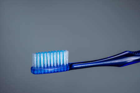 Budget toothbrush blue. Brush on a gray background. Cleaning tool.の写真素材