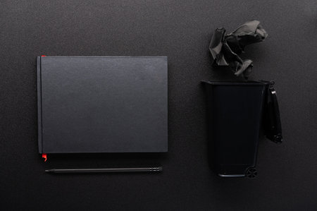 Black Mockup. Black notebook and black pencil. Black items on the table. Trash and spoiled sheet of...
