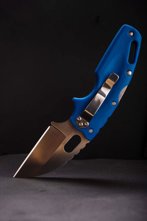 Folding pocket knife with blue plastic handle. Knife with a clip for carrying. Knife on a black...