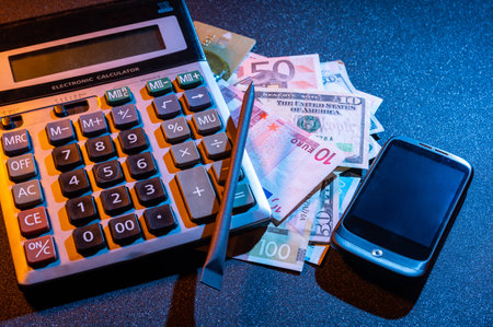 Calculator, money and smartphone. Count money. Calculate profits and costs. Income and taxes. Top view at an angle.の写真素材