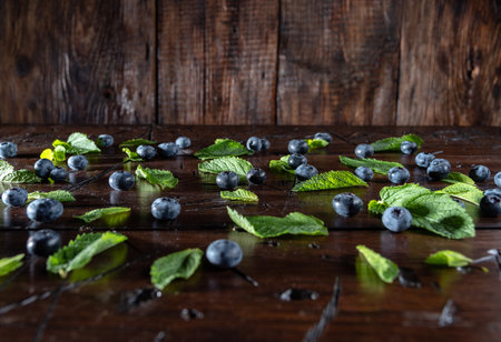 Blueberries are scattered on the table. Blueberries and leaves are scattered on the table. Angle view. Wooden background.の写真素材