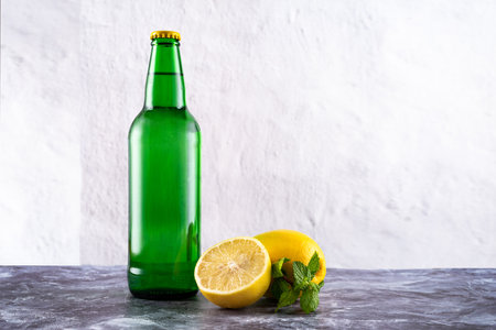 Green glass bottle and lemons with mint. Sweet sparkling water. Lemonade. Front view.の写真素材