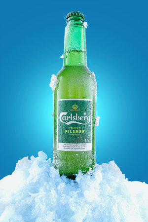 Kyiv, Ukraine - July 2, 2022: beer bottle Calsberg. Chilled beer with condensate and ice. Blue background.のeditorial素材