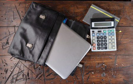 Black leather briefcase and laptop. Briefcase and computer on the table.