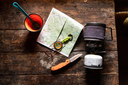 Kitchen table in a hut. Map and compass on the table. Route planning. Camping kitchen and utensils on the table.の写真素材