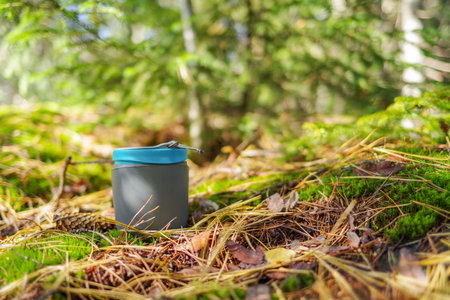 Tourist mug on the ground. Tourist dishes on moss. Hiking dishes. Hiking mug for drinks.の写真素材