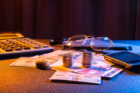 Financial workspace with coins, money, calculator and glasses. Glasses and calculator on the table with money. Finance and accounting.の写真素材