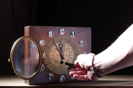 Start time with a key. Clockwork key in hand. Make time. Hand and key for watch winding.の写真素材