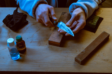 A craftsman checking the edge of a sharpened old knife with a wooden handle. Workspace background...