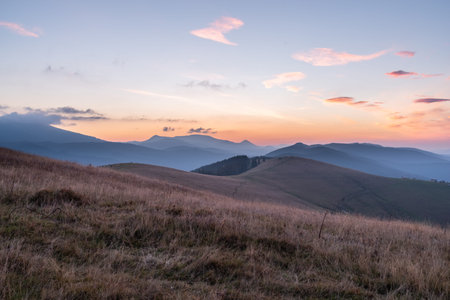 Majestic mountain sunrise with pink and purple sky and layered hills.