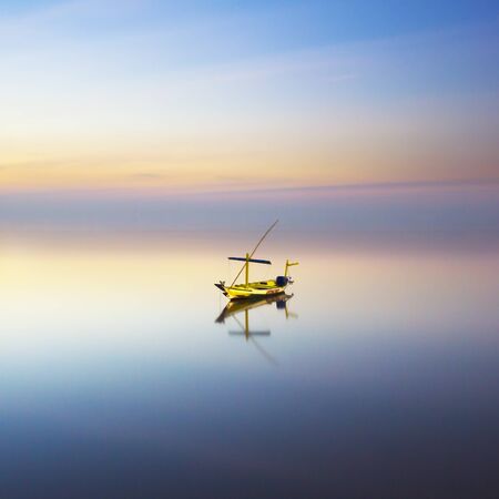 Fishing boat on a beach during beautiful sunrise taken with long exposure photographyの写真素材